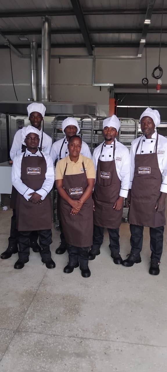 Tastebell bakers standing together beside the baking racks